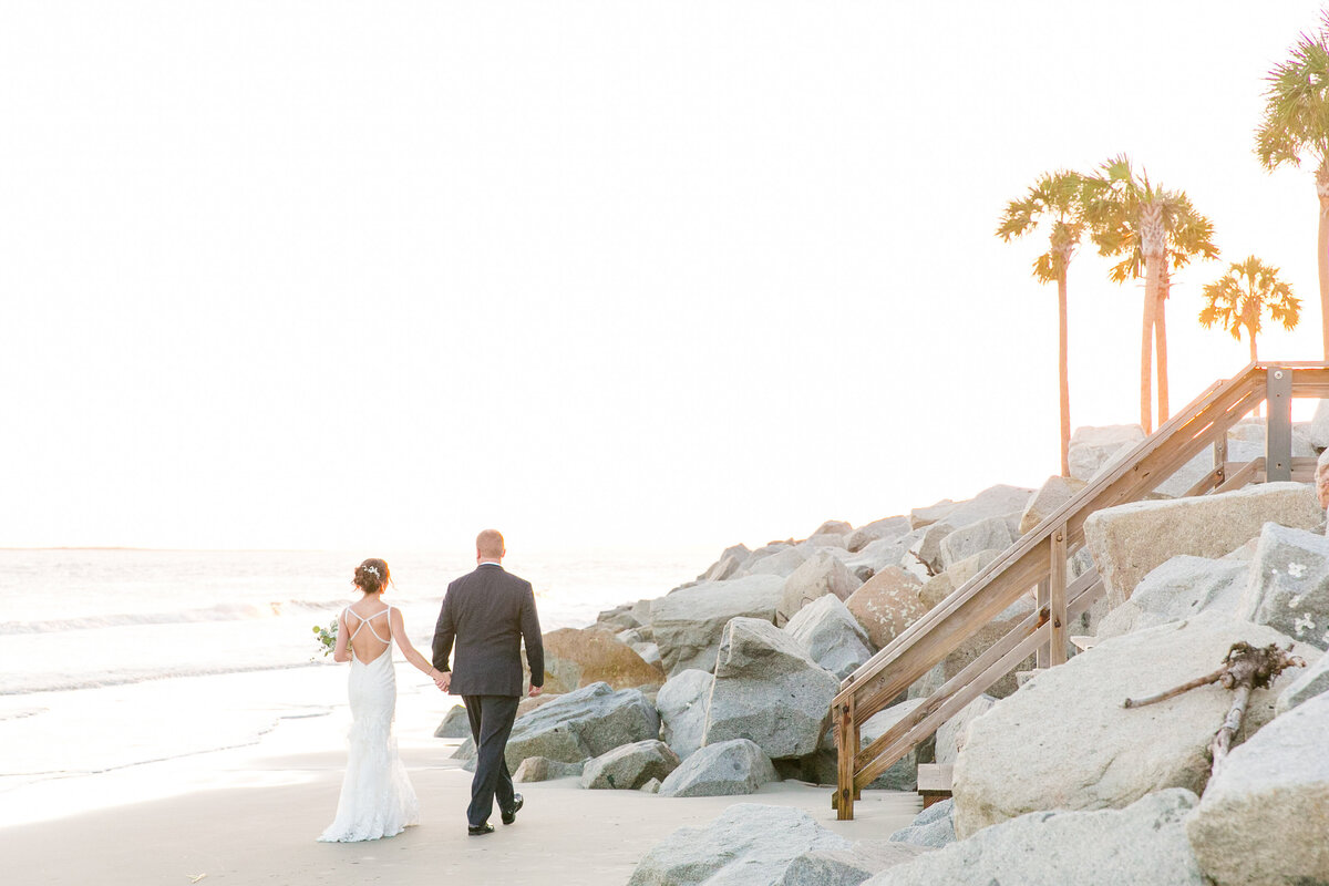 bride and groom walk into the sunset on the beach