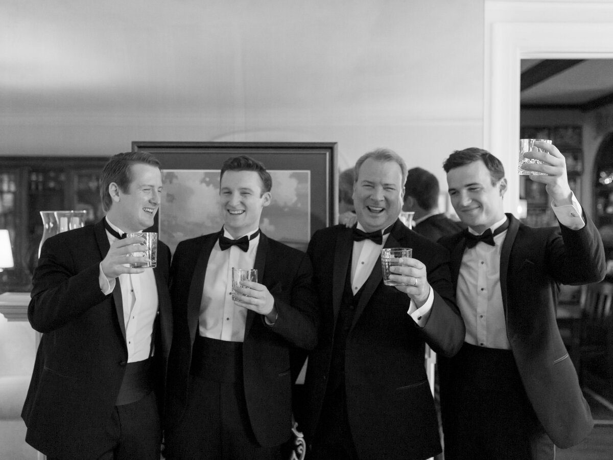 Groomsmen happily holding drinks photographed by Chicago editorial wedding photographer Arielle Peters