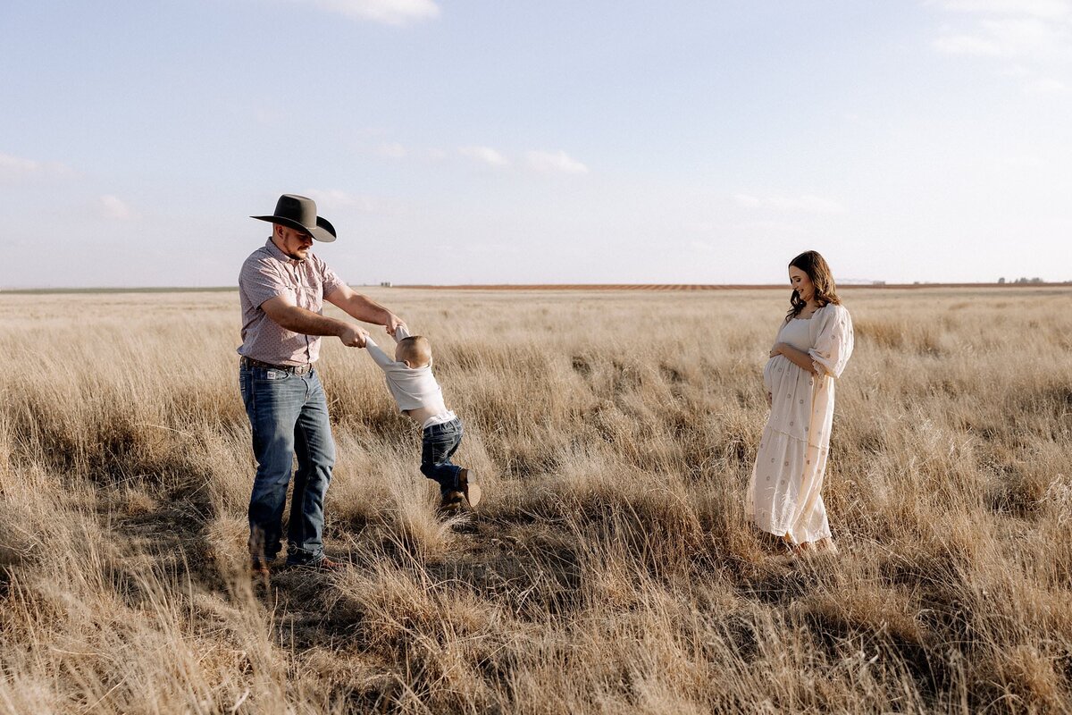 dad swinging son maternity photo of mom holding her belly smiling down at her  belly