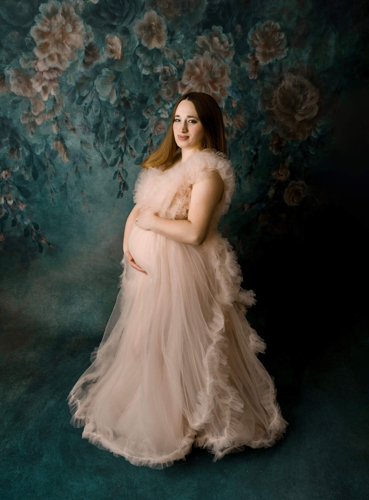 Maternity photo of a  young woman wearing a beautiful pink maternity gown