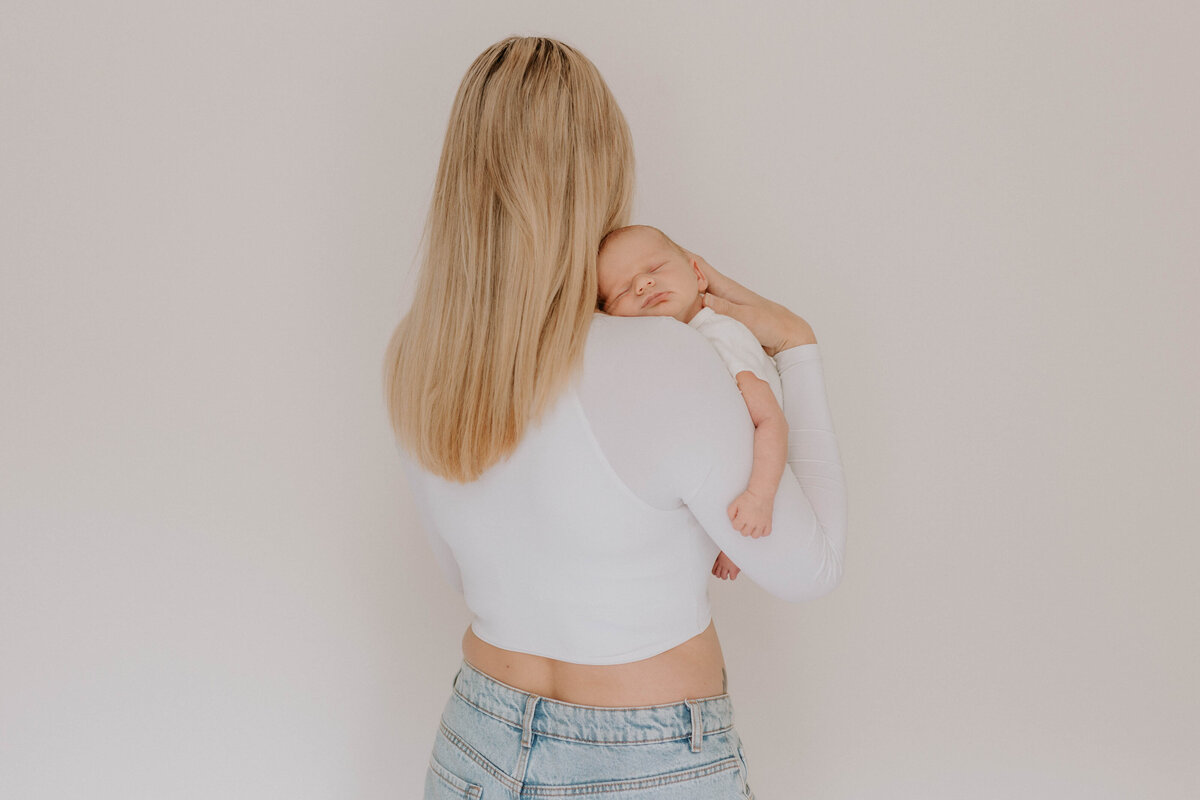 Newborn baby asleep on mothers shoulder