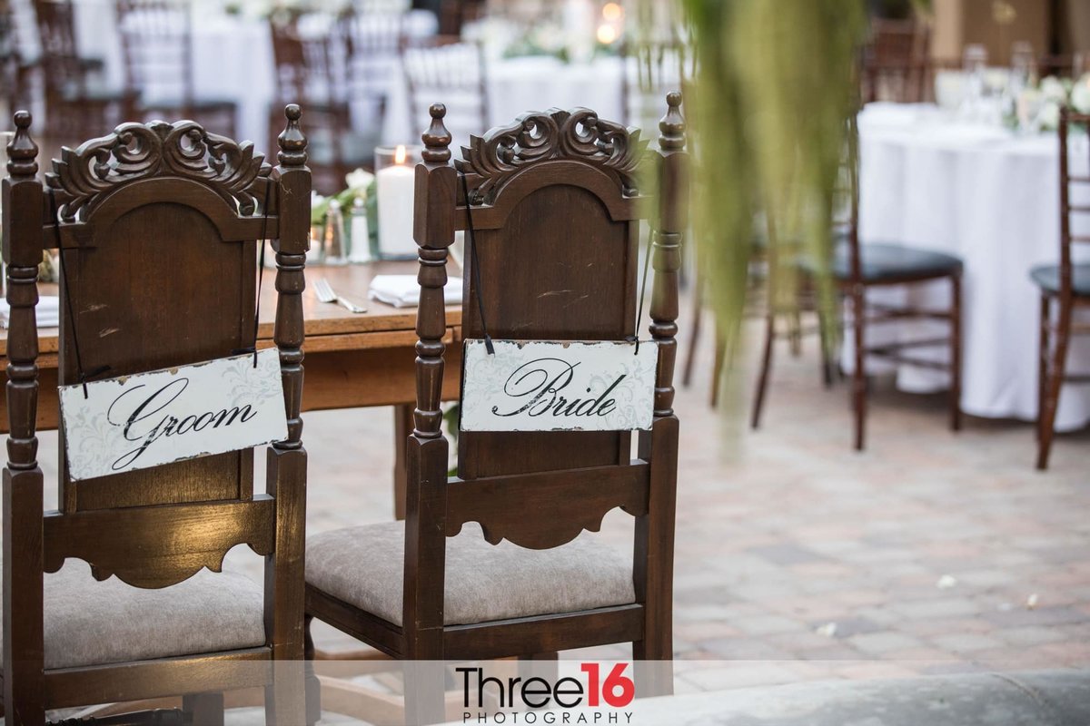 Bride and Groom signs hang from their wedding reception chairs