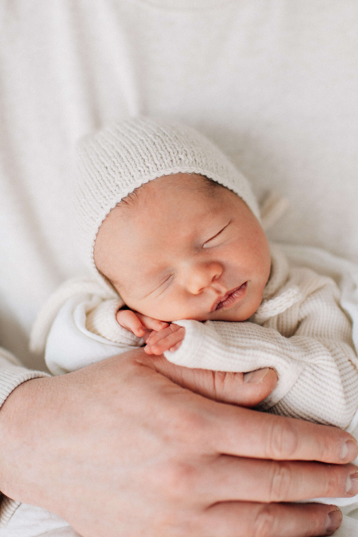 baby in dad's hands wearing a knit bonnet