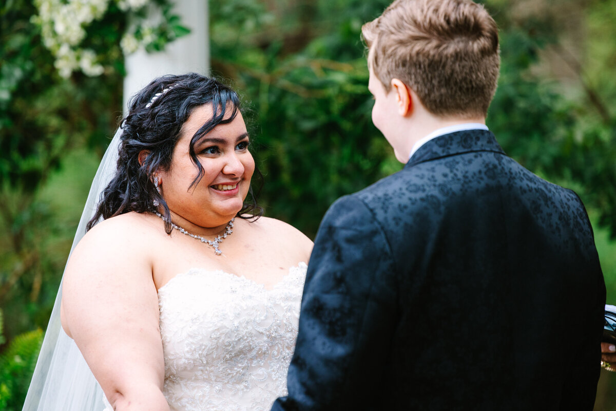 Two brides smiling hand in hand at the alter