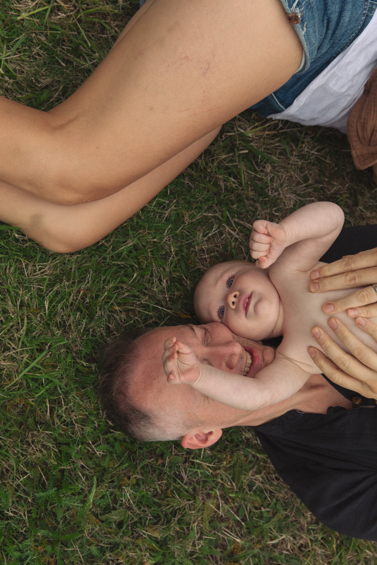 Parents and child laying on grass, shot from above. Relaxed and natural family photography in Portland and Nashville.