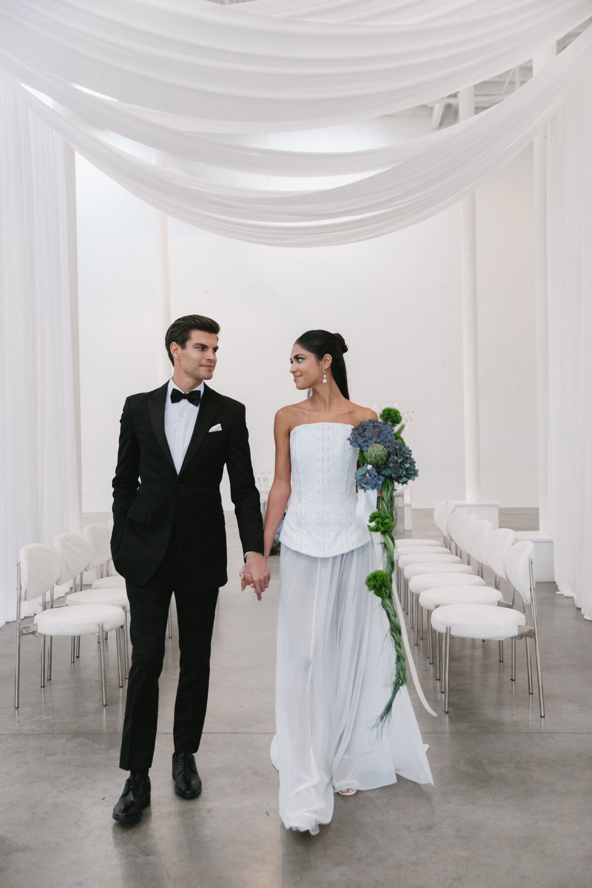 Bride and groom standing together holding a sculptural hydrangea bouquet at a modern New York City wedding shoot.