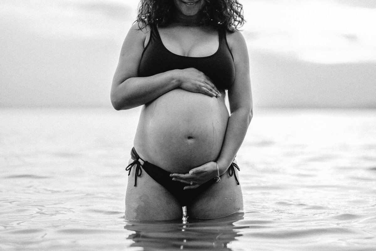 Pregnant woman paddles in the sea during maternity photoshoot