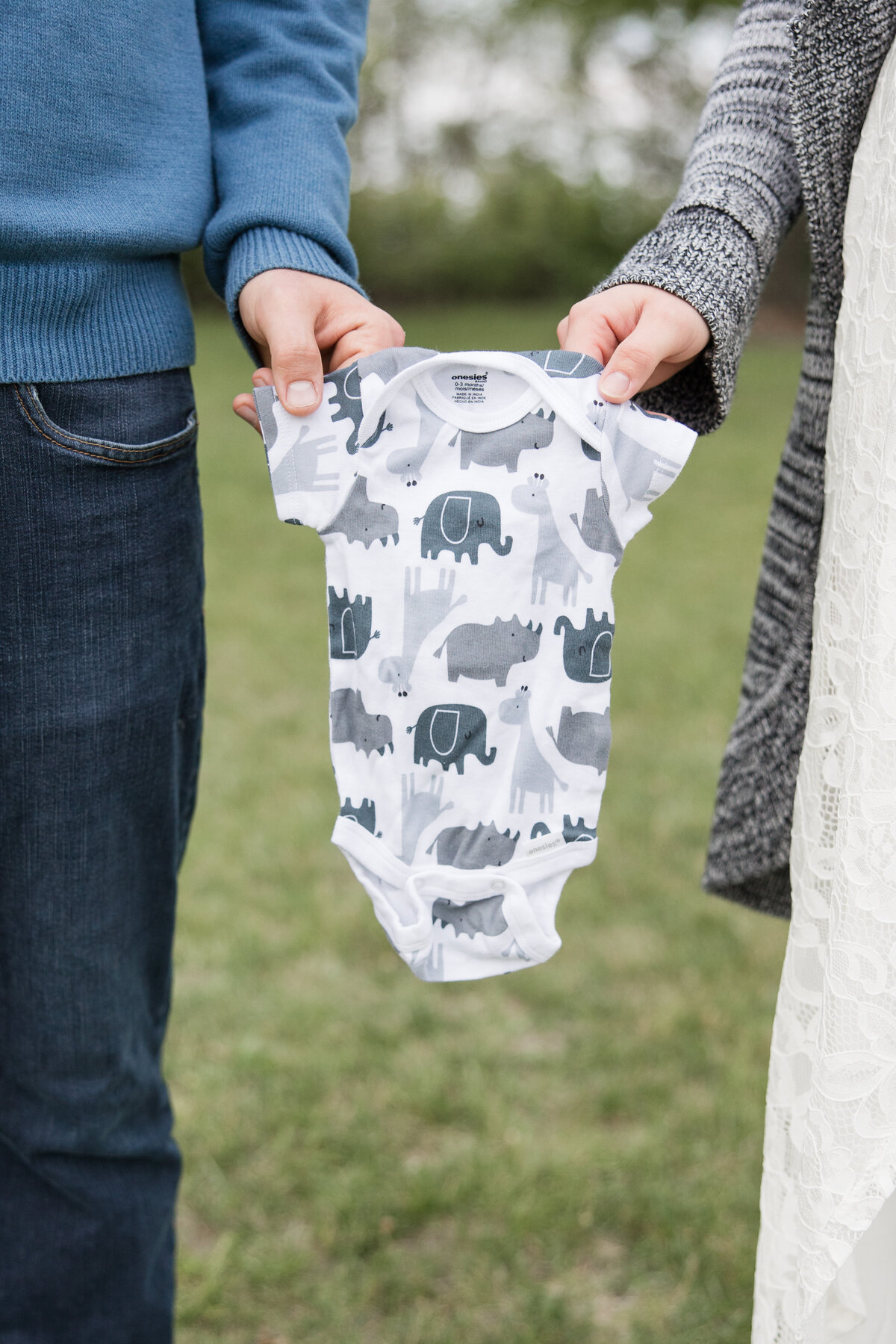 Expectant couple holding a baby's onesie