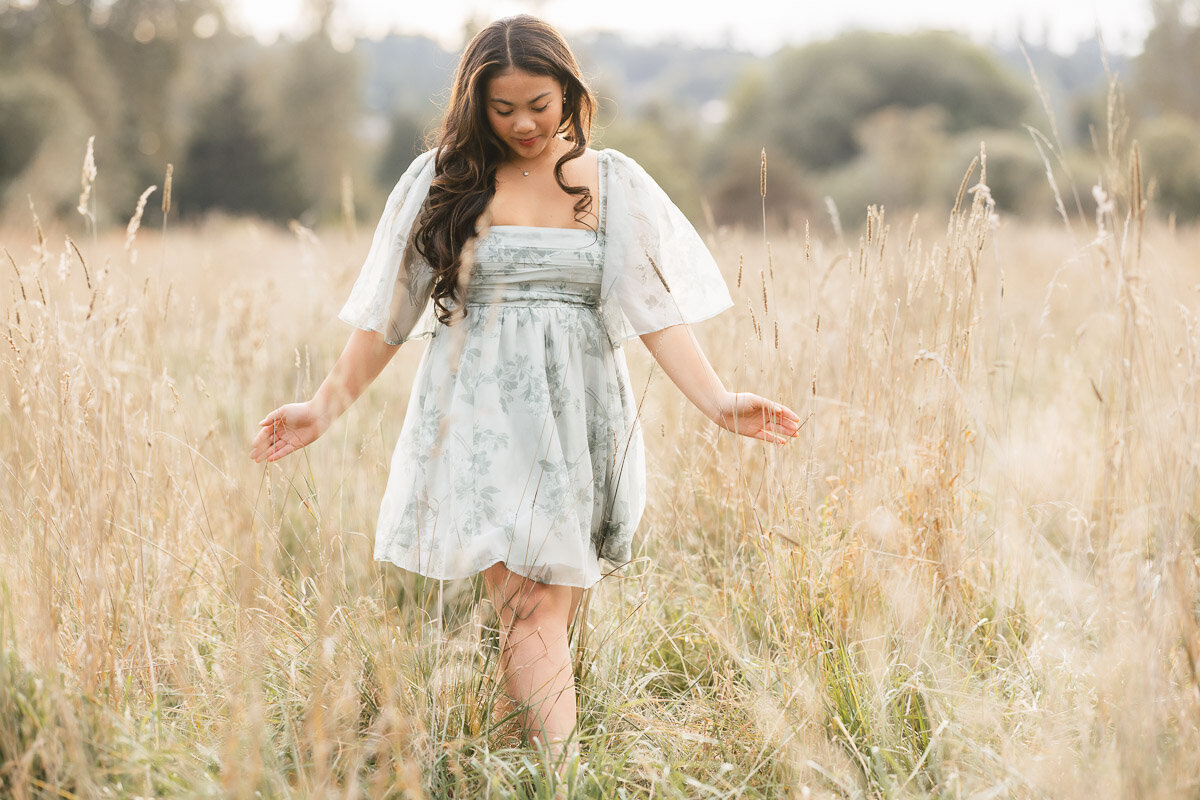 Young girl in a dress walking through a grassy field.