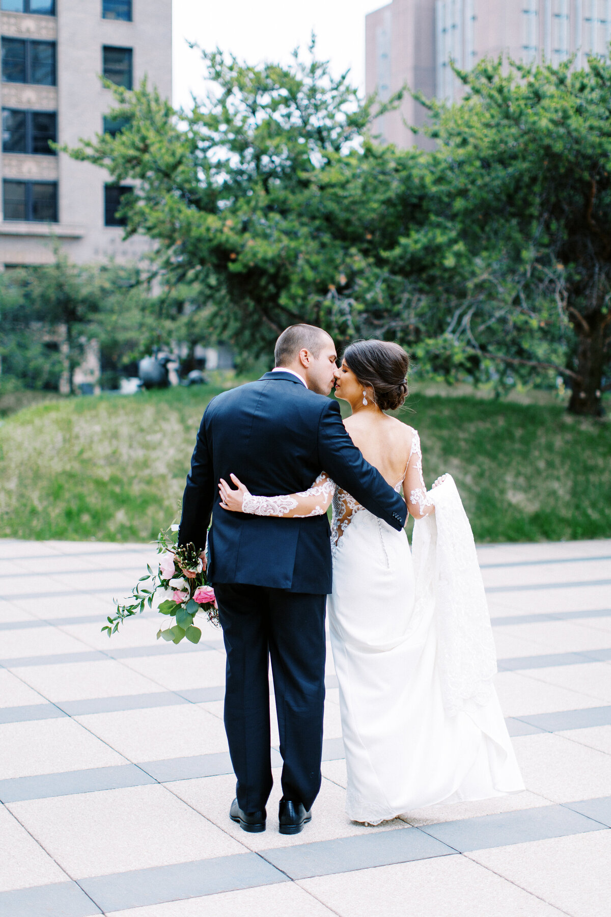 bride and groom walking arms around each other and going for a kiss in Minneapolis