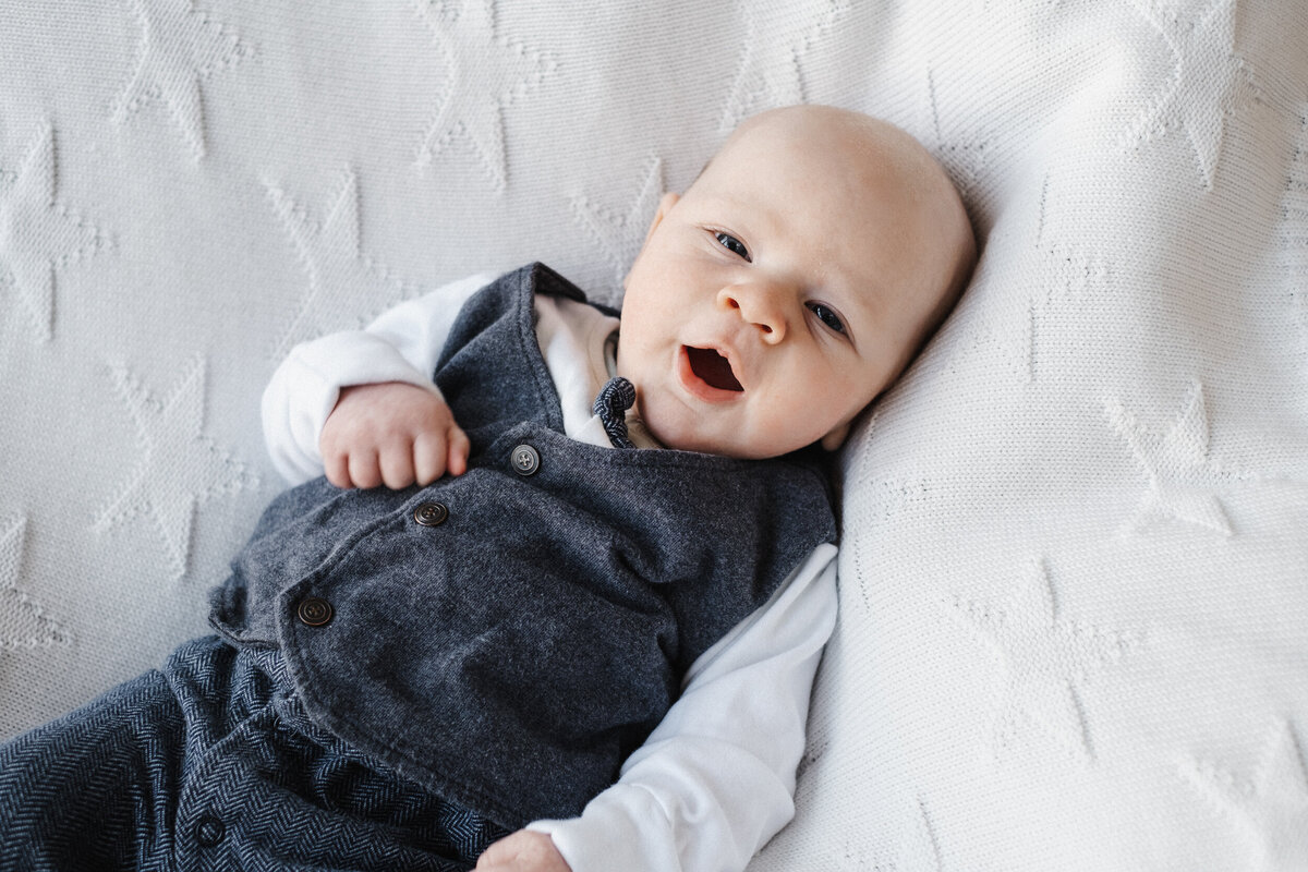 Cute bald baby laying on blanket makes a yawning face