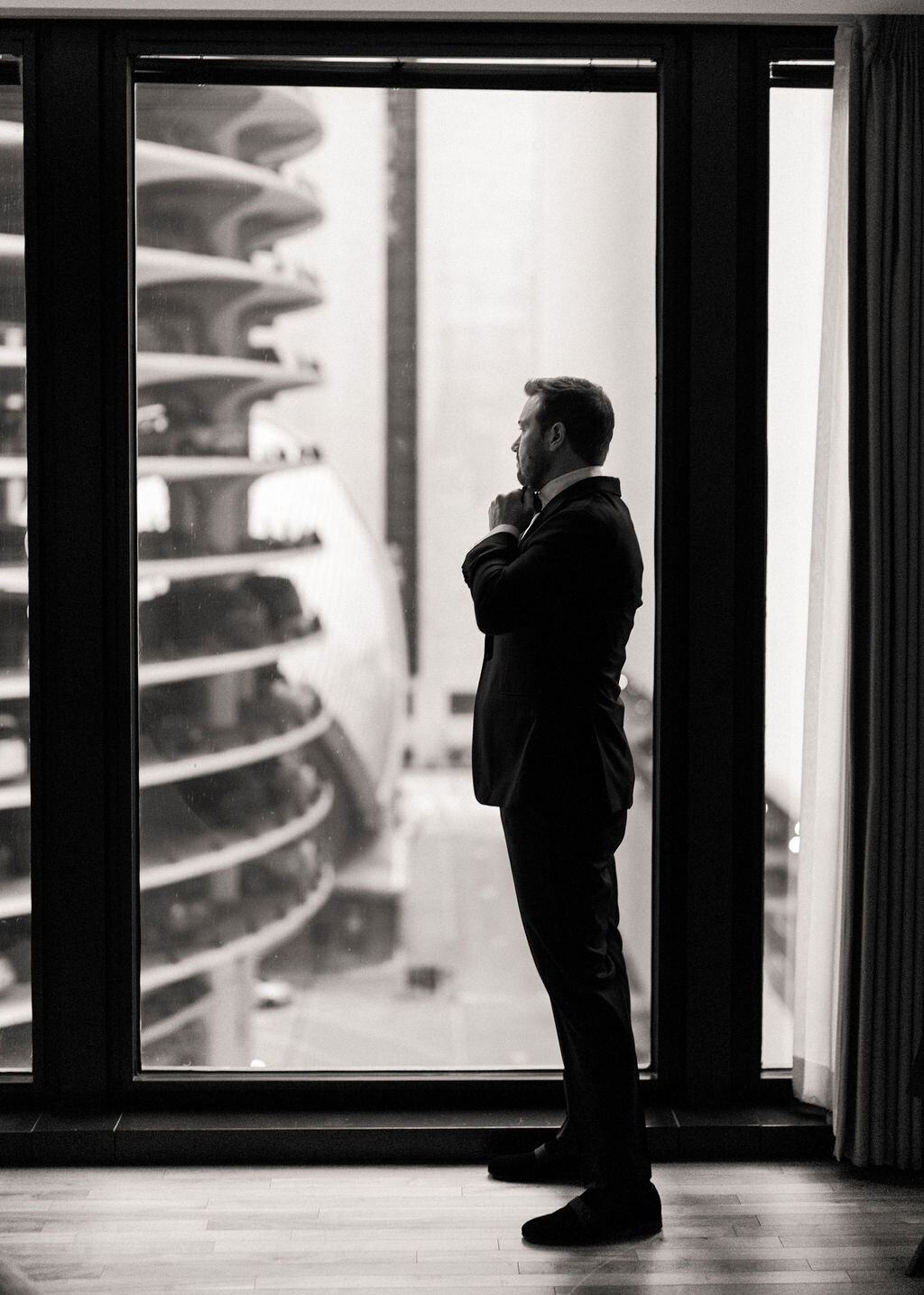 Photo of the groom looking out the window in downtown Chicago. 