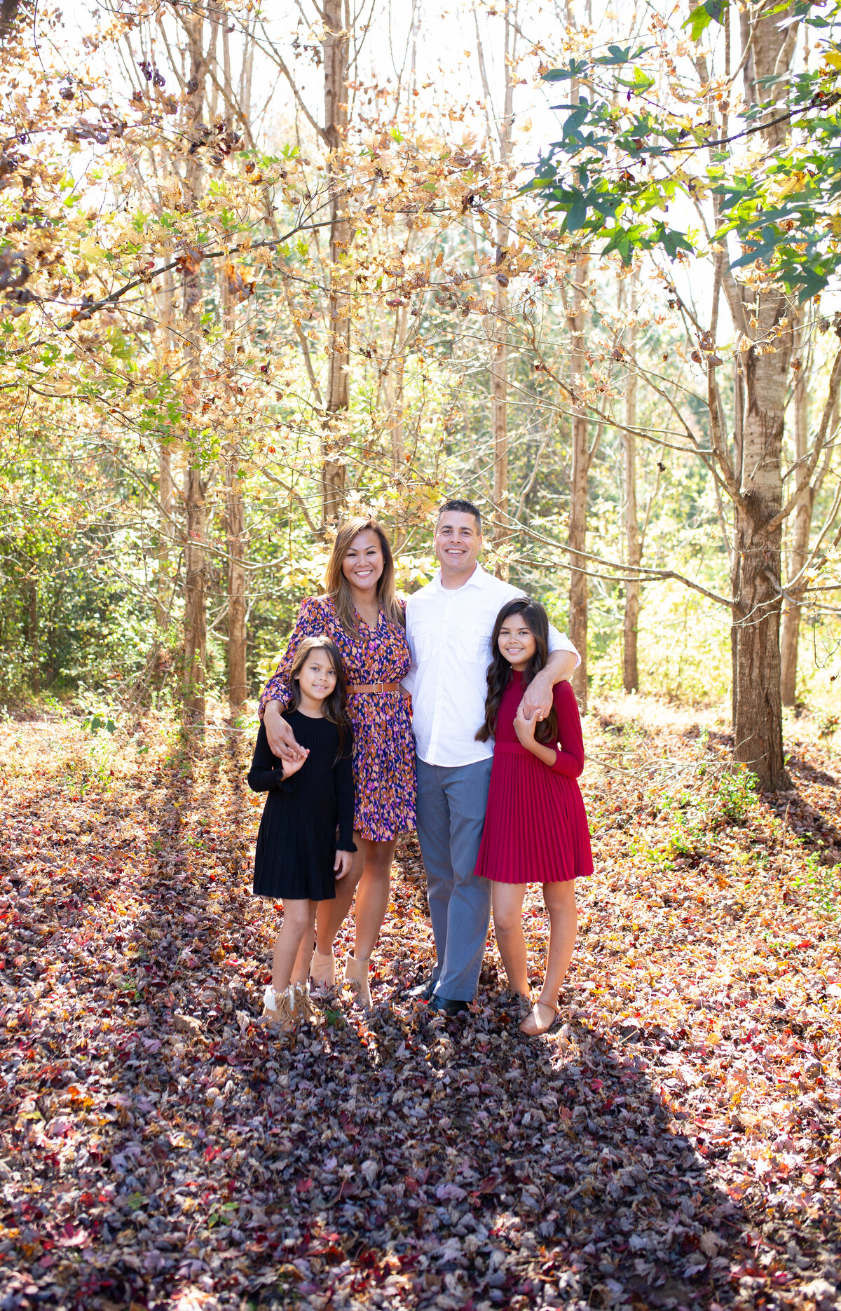 parents and their two daughters posing for a fall family portrait