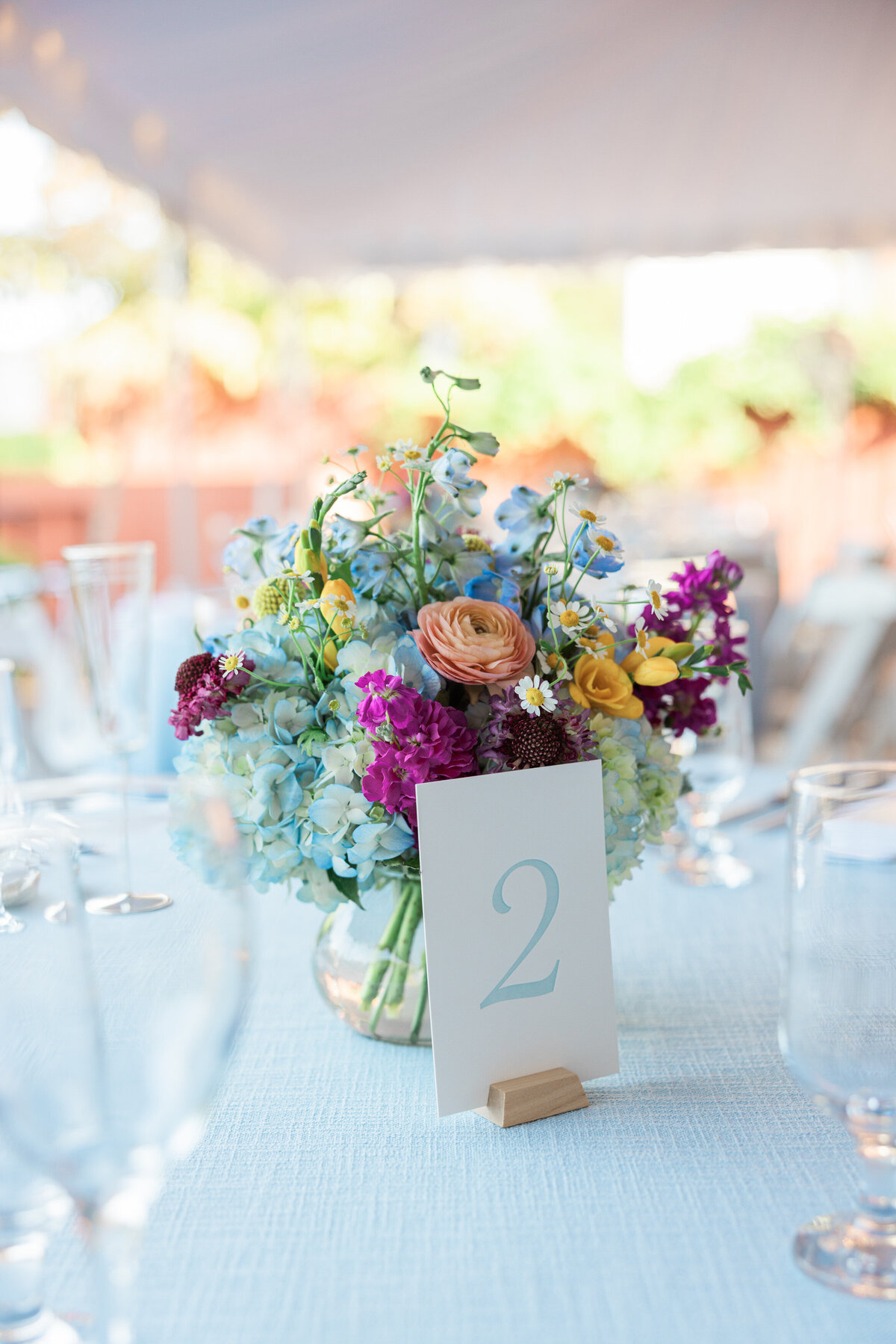 A table number with a colorful bouquet behind it