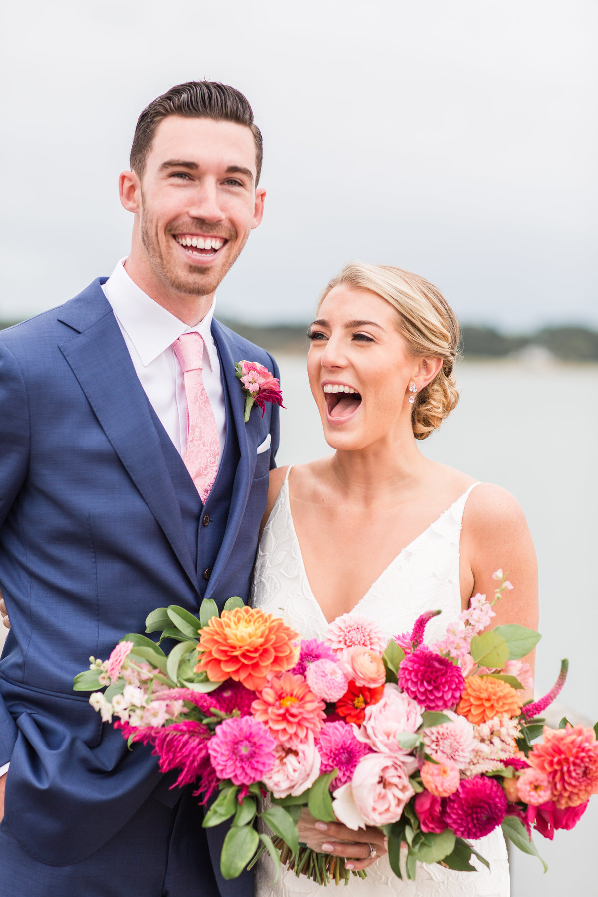 Bride and Groom laughing while bride holds bright bouquet