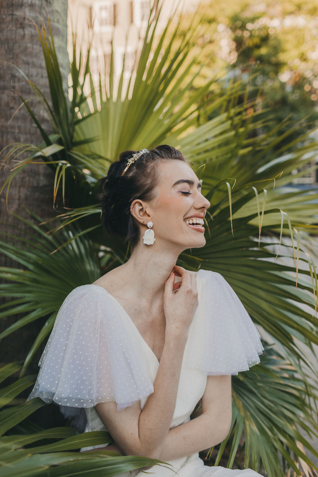 The swiss dot net flutter sleeves of the Mai wedding dress style pop against the green of the palmettos in downtown Charleston.