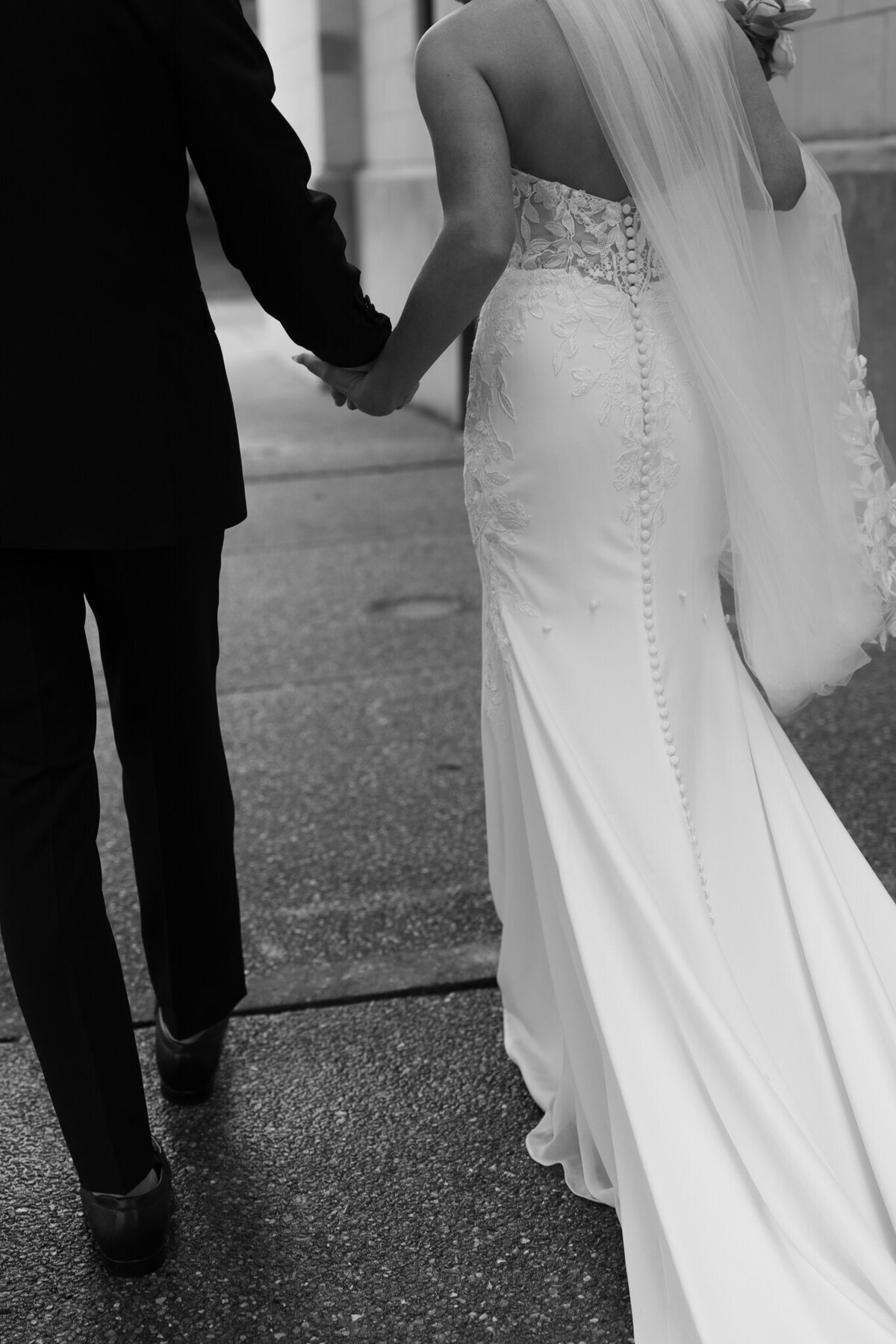 Back view of bride and groom holding hands walking