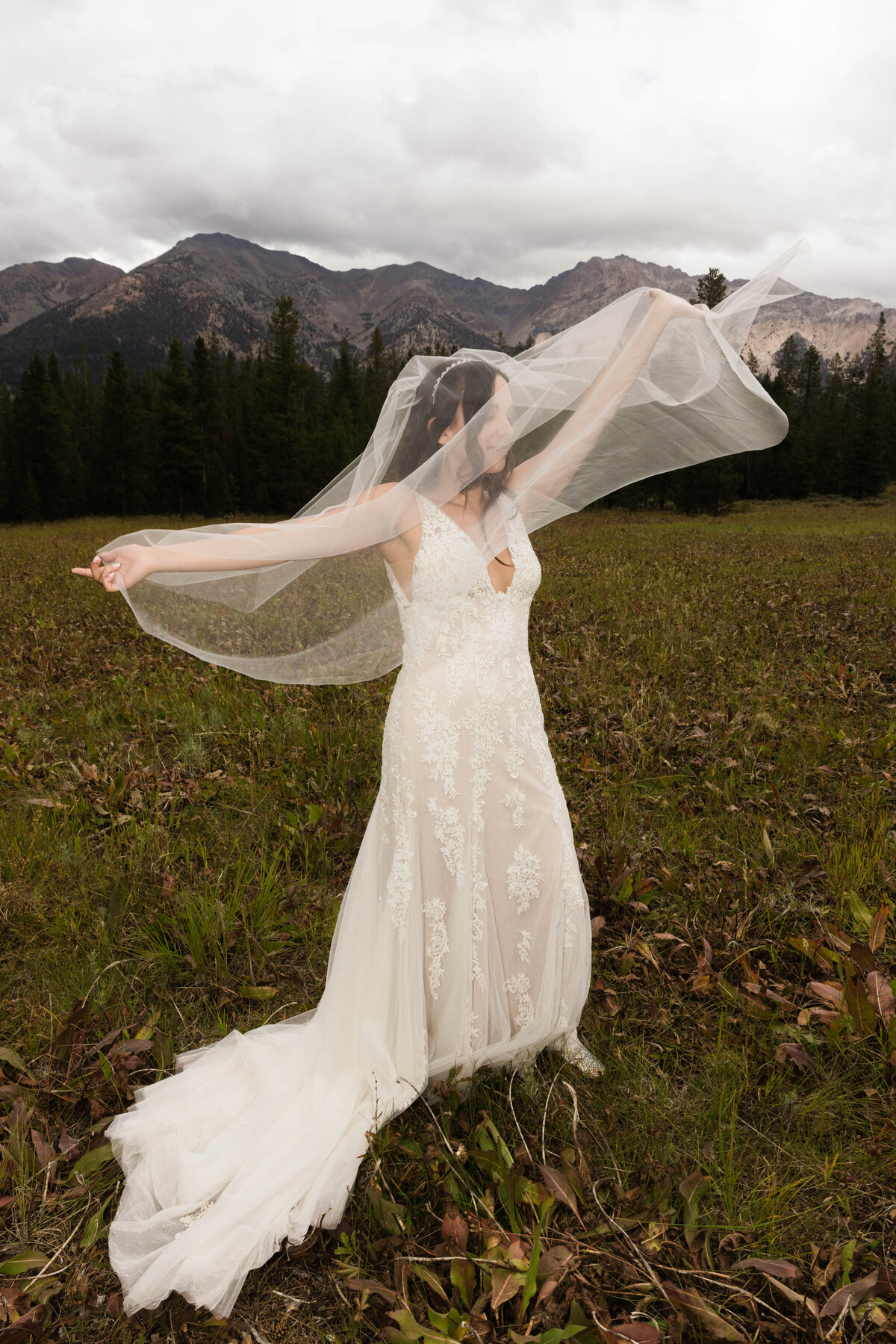 Bride holding veil in the air letting the wind catch it