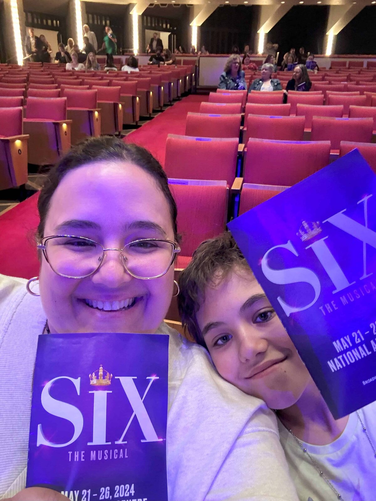 Valerie Doucette and her eldest daughter holding up a poster for Six The Musical before the show starts