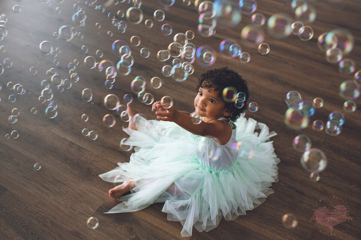 baby girl in tulle skirt popping bubbles
