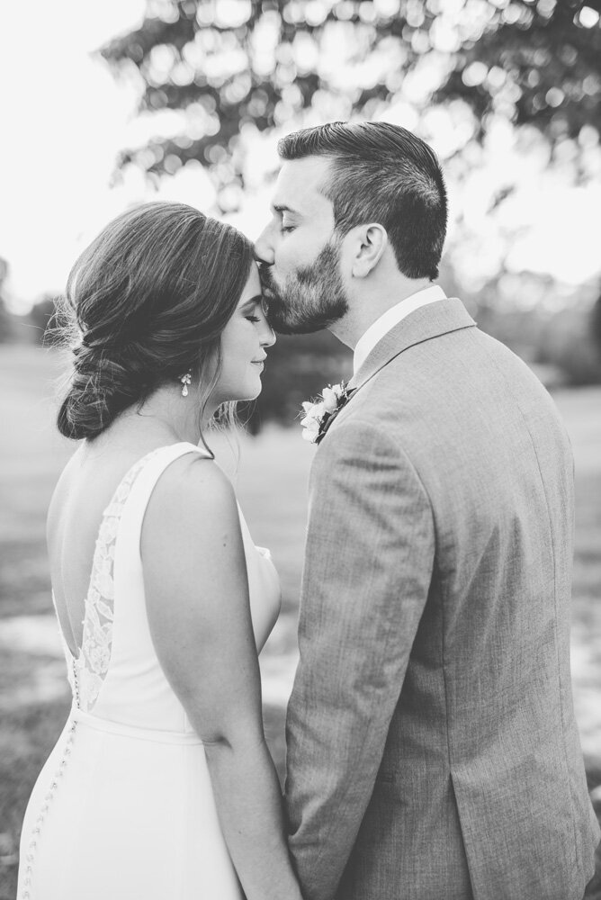 Groom kissing bride on forehead