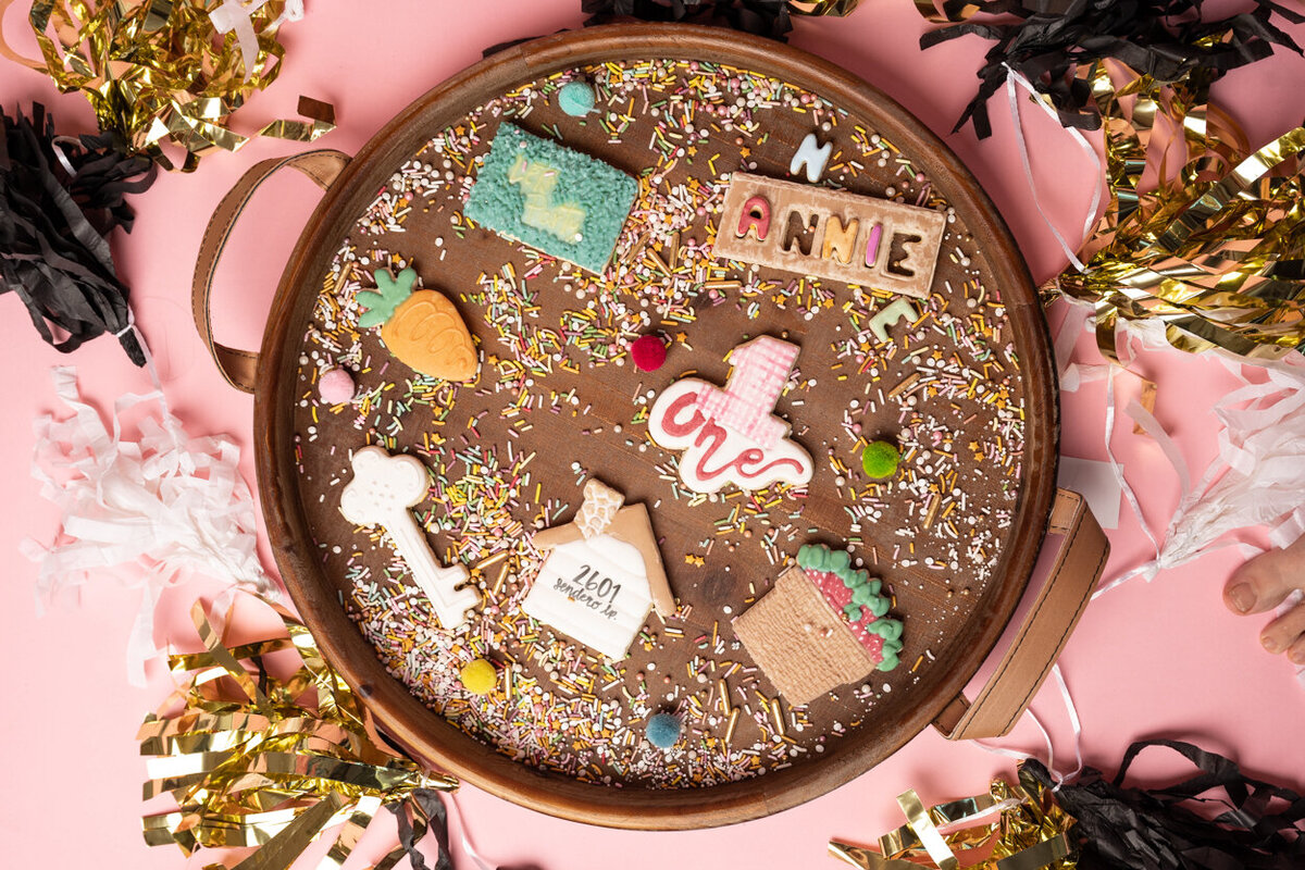An image of a cookie tray on a pink base with party flavours around