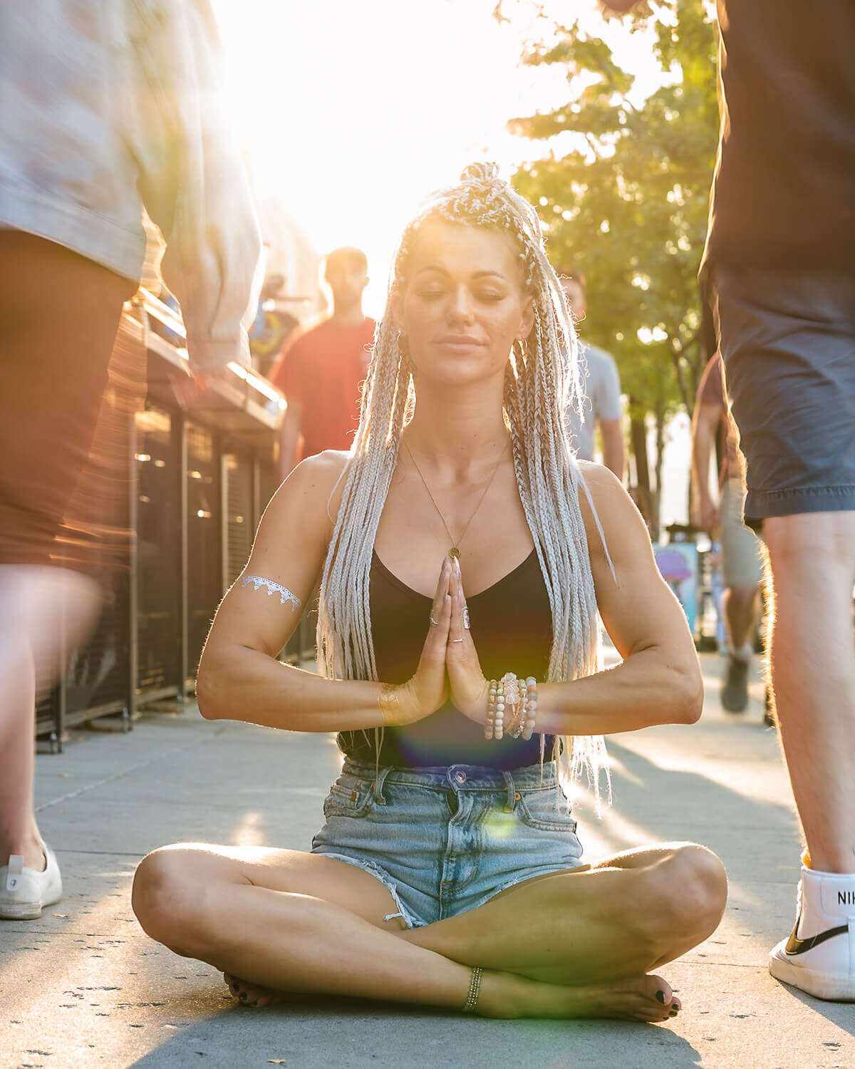 spiritual woman meditating on busy street with sun in the background