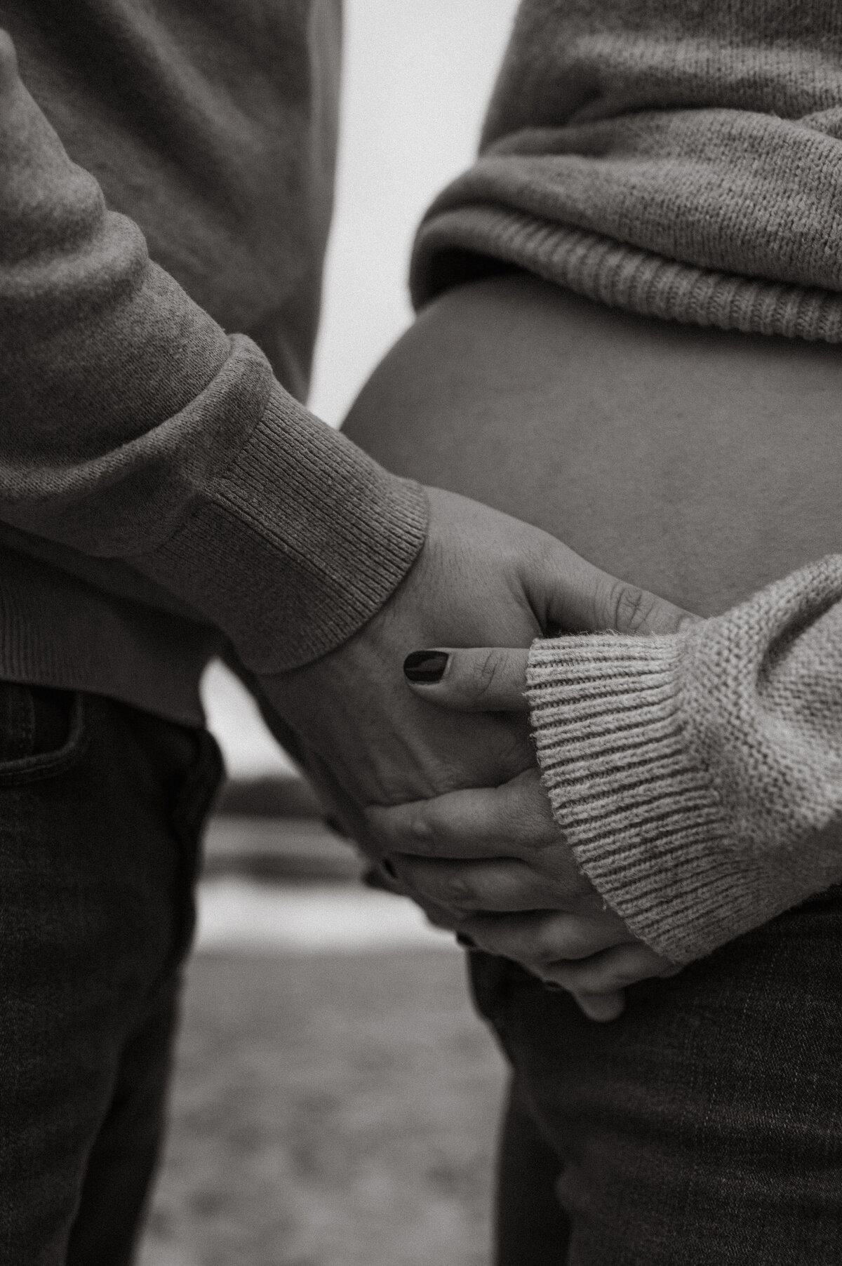 Koppel houdt handen op zwangere buik van vrouw tijdens zwangerschapsshoot in Antwerpen