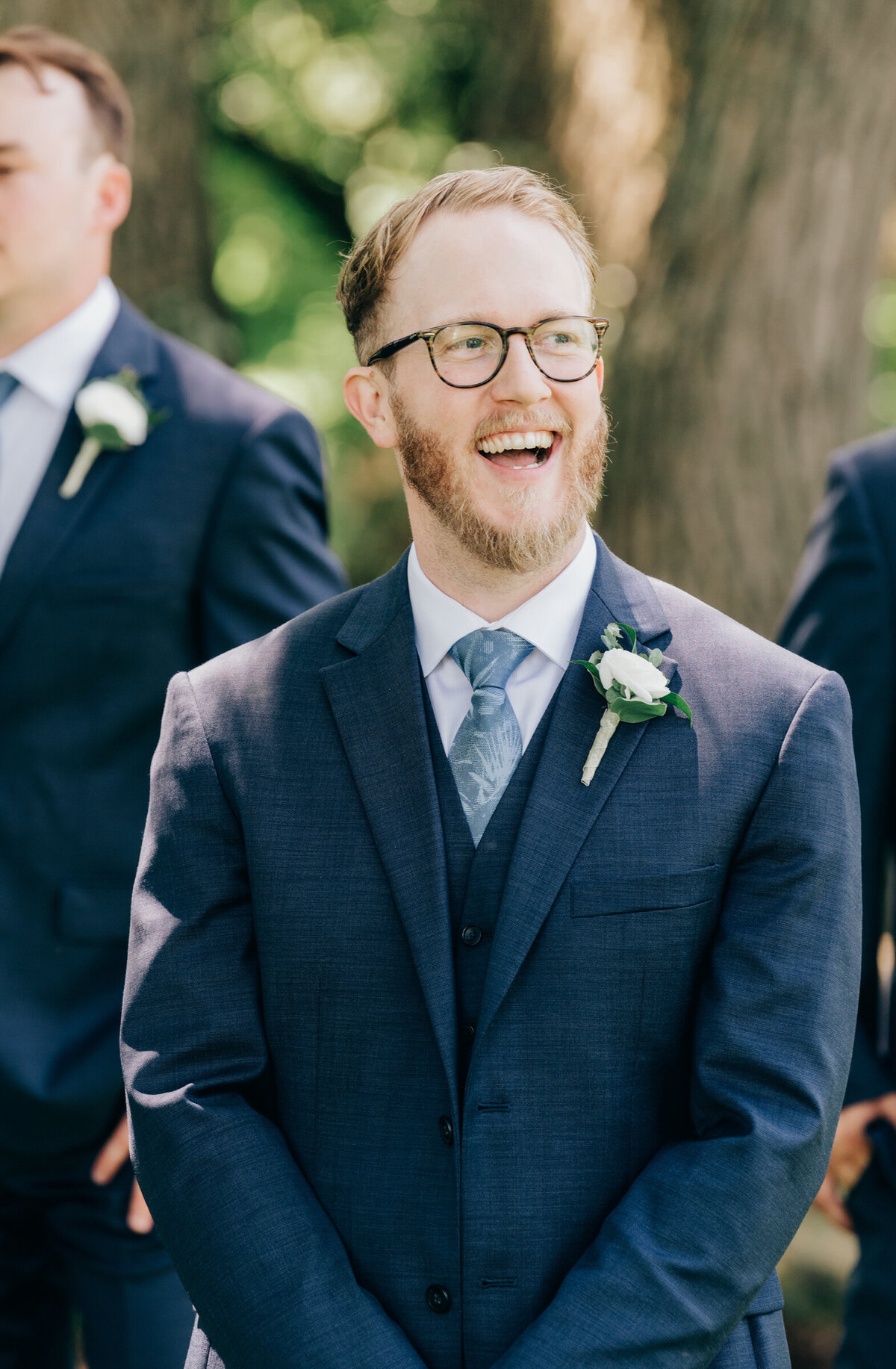 Candid photo of groom laughing during outdoor wedding portraits photographed by Nova Markina