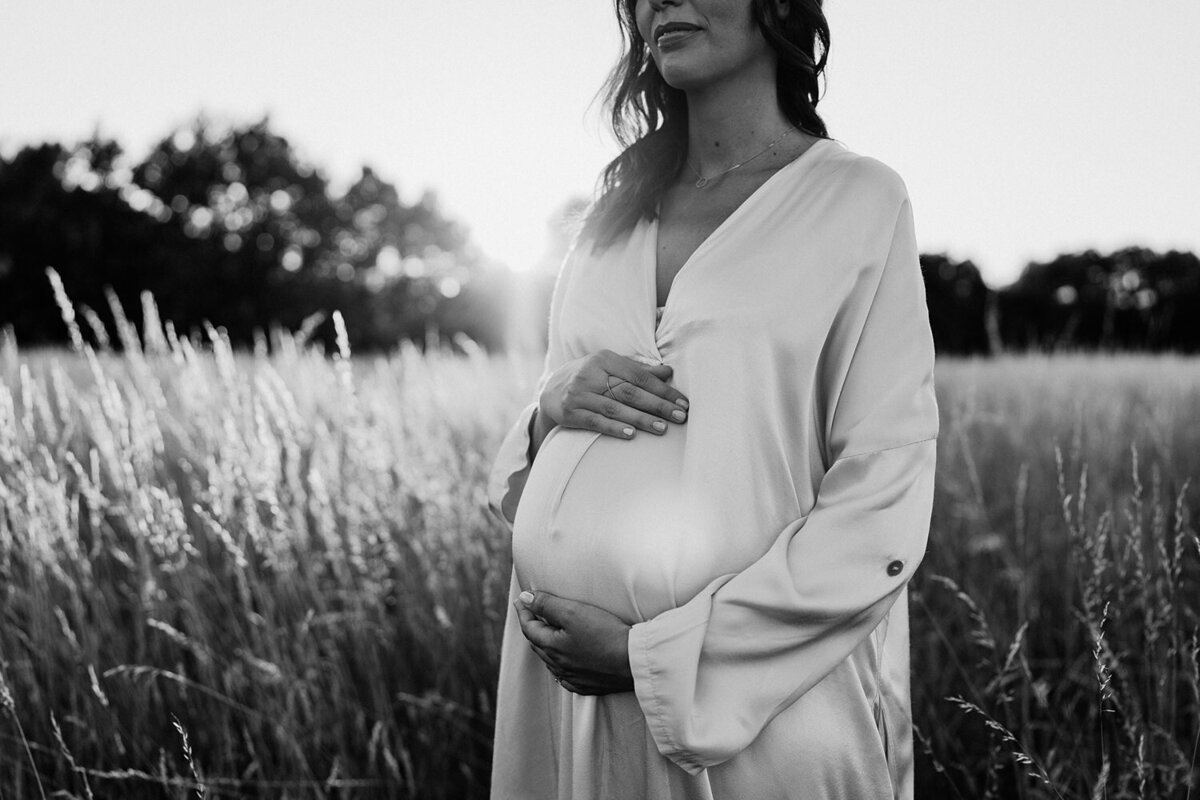 Zwangerschapsfoto in een veld tijdens het gouden uur