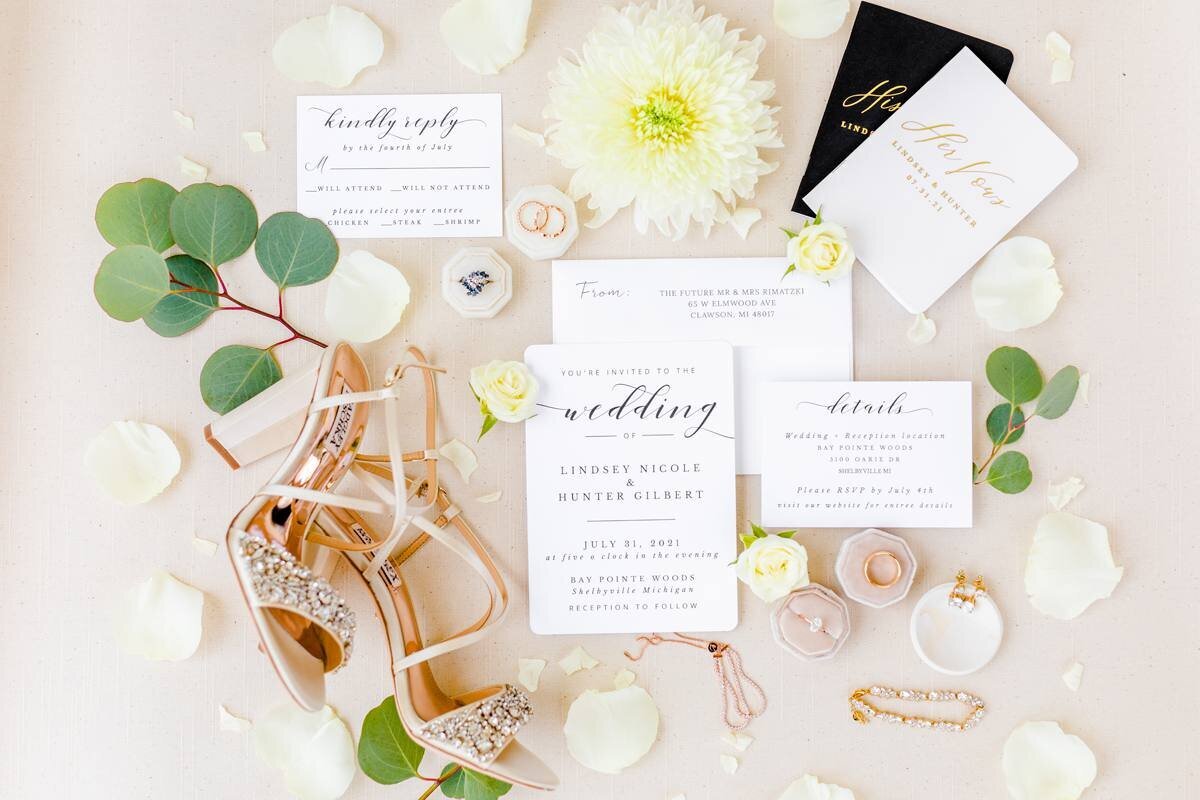 flatlay photo of bridal details with wedding invitation and badgley mischka bridal shoes