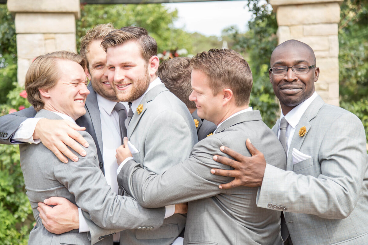 A group of groomsmen hugging and congratulating groom on his wedding day , wedding photography by Jessica Bowles