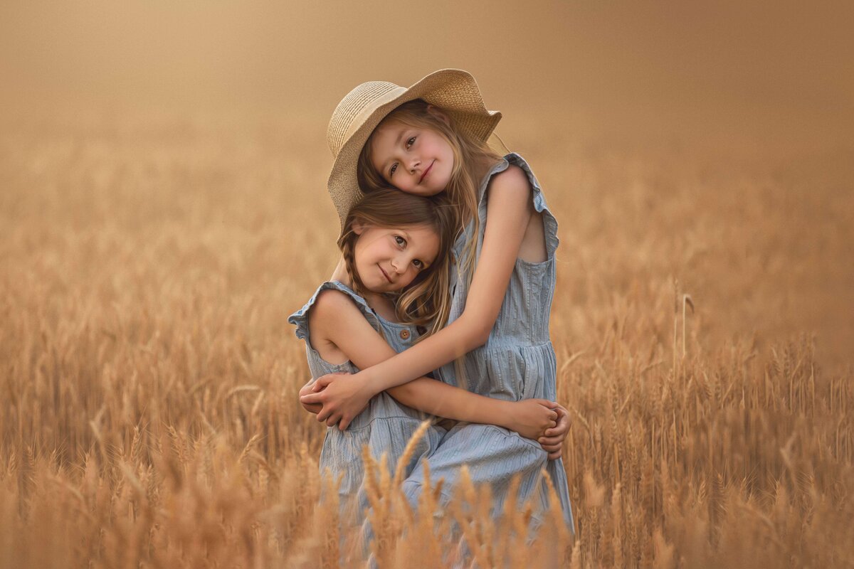 Sisters hugging in wheat field