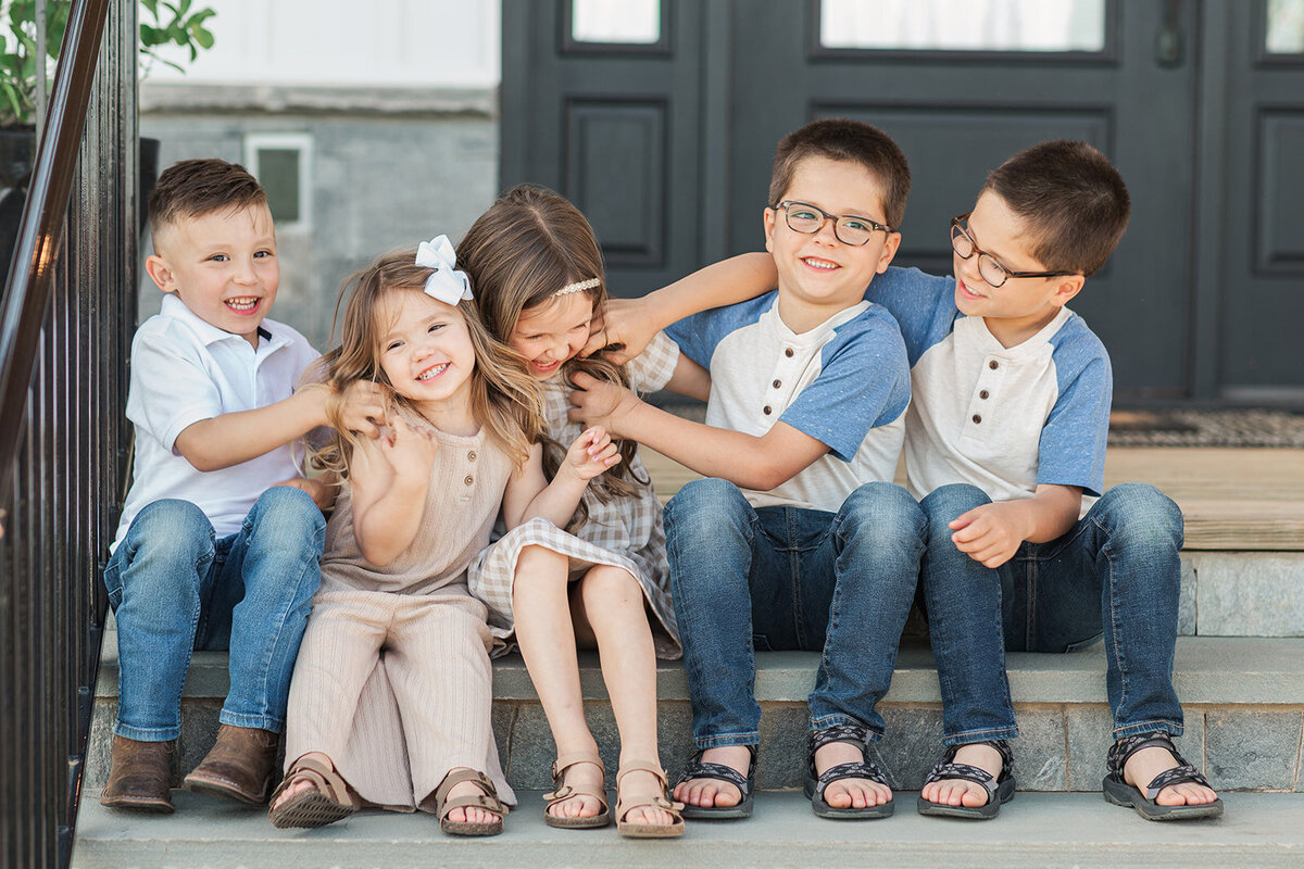 Grandkids sitting on step laughing and smiling during extended family photo session