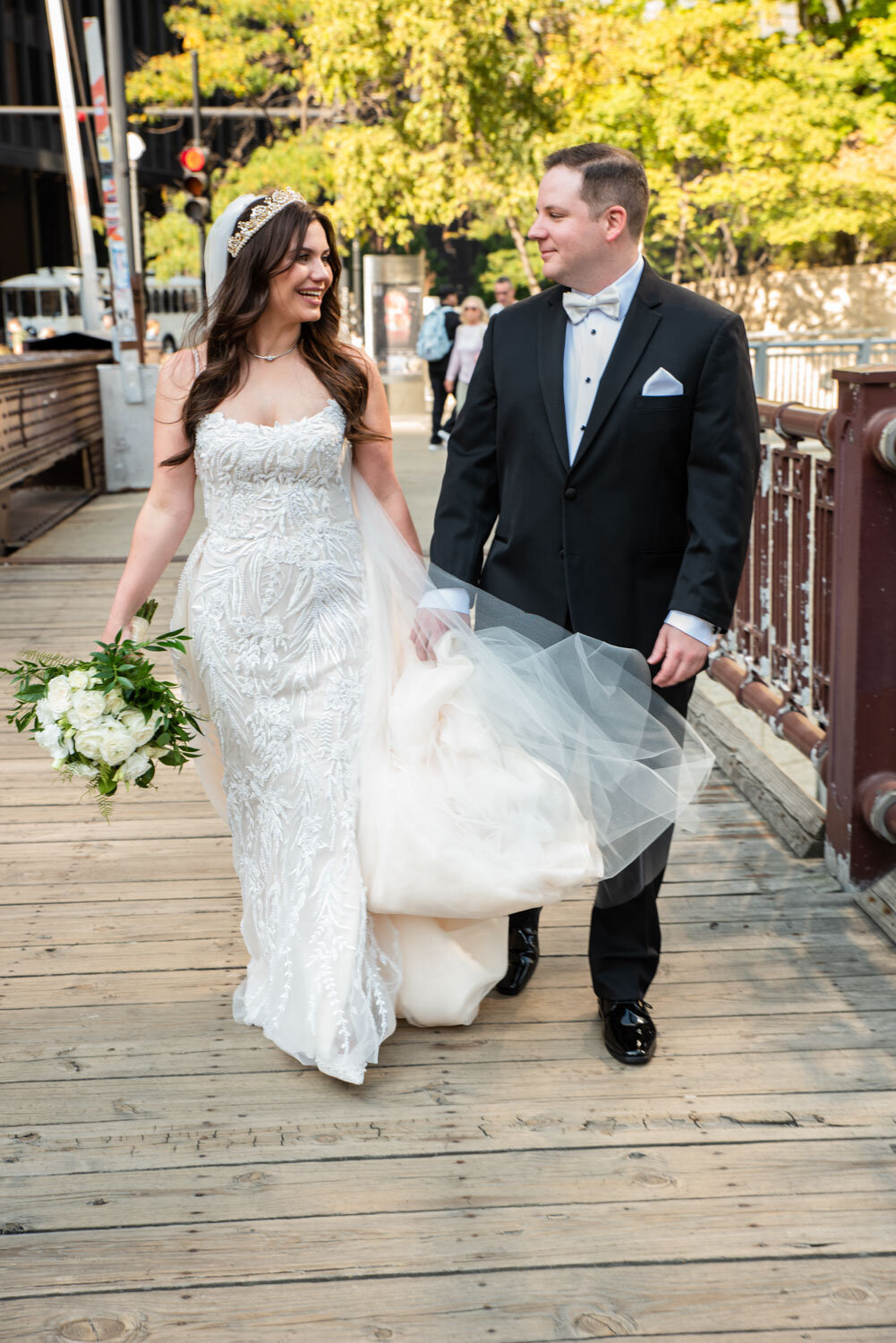 A bride and groom are walking on a wooden bridge