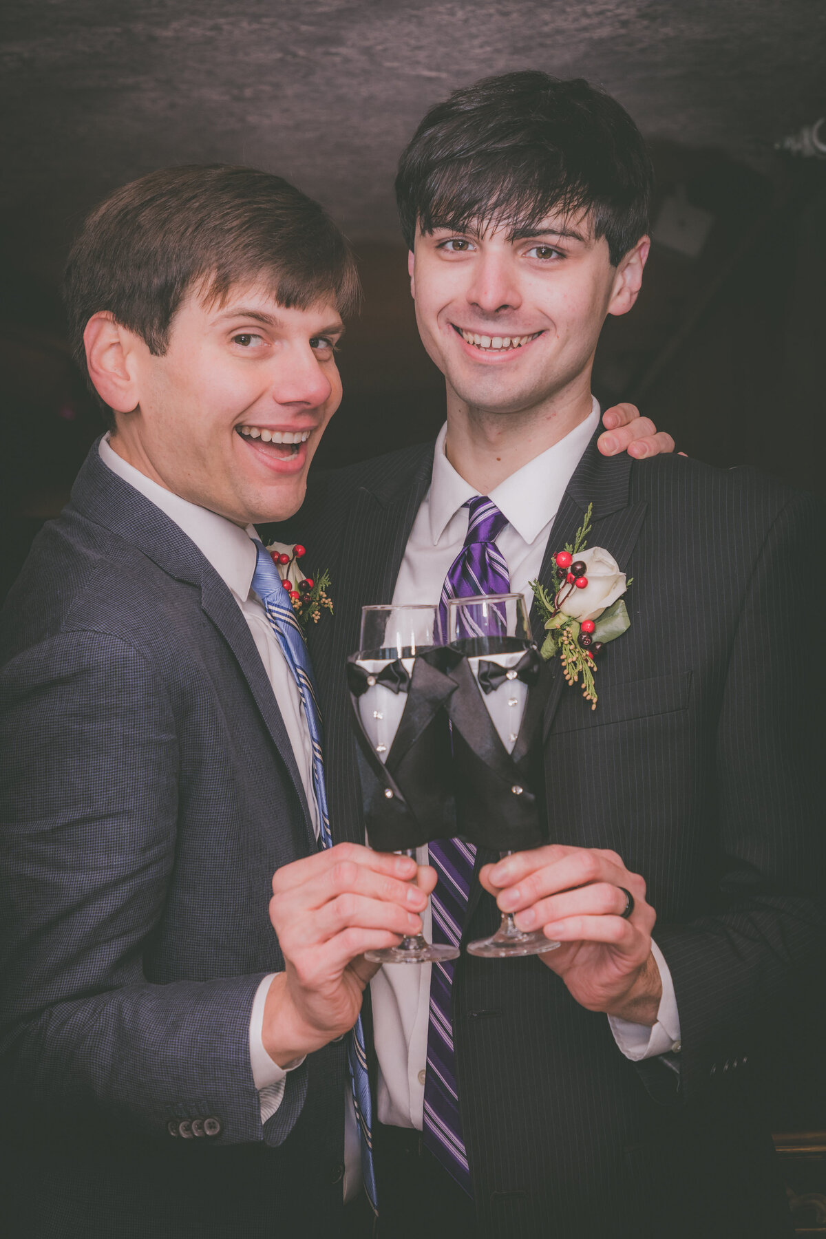 Two grooms do cheers with champagne to celebrate their elopement.