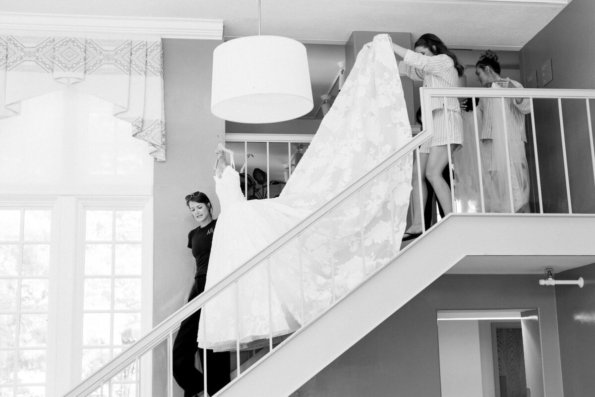 women carrying a wedding dress down the stairs