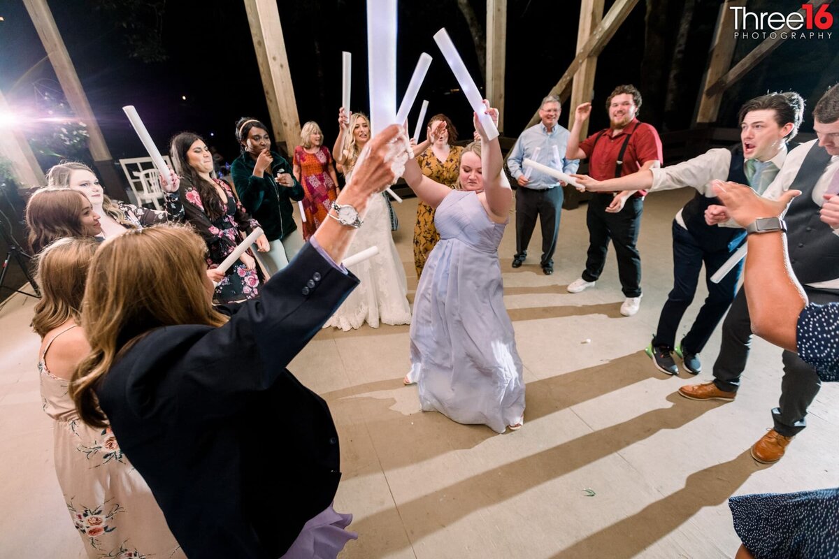 Wedding guest dances in the middle of others with light sabre