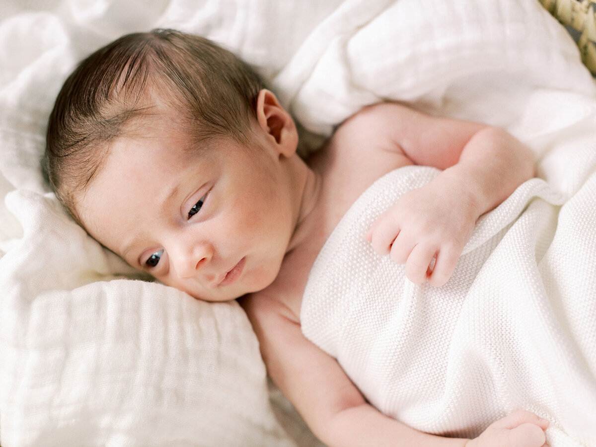 A baby wrapped in a blanket looking to the left during a newborn photography session in Richmond by Katie Stansfield Photography.