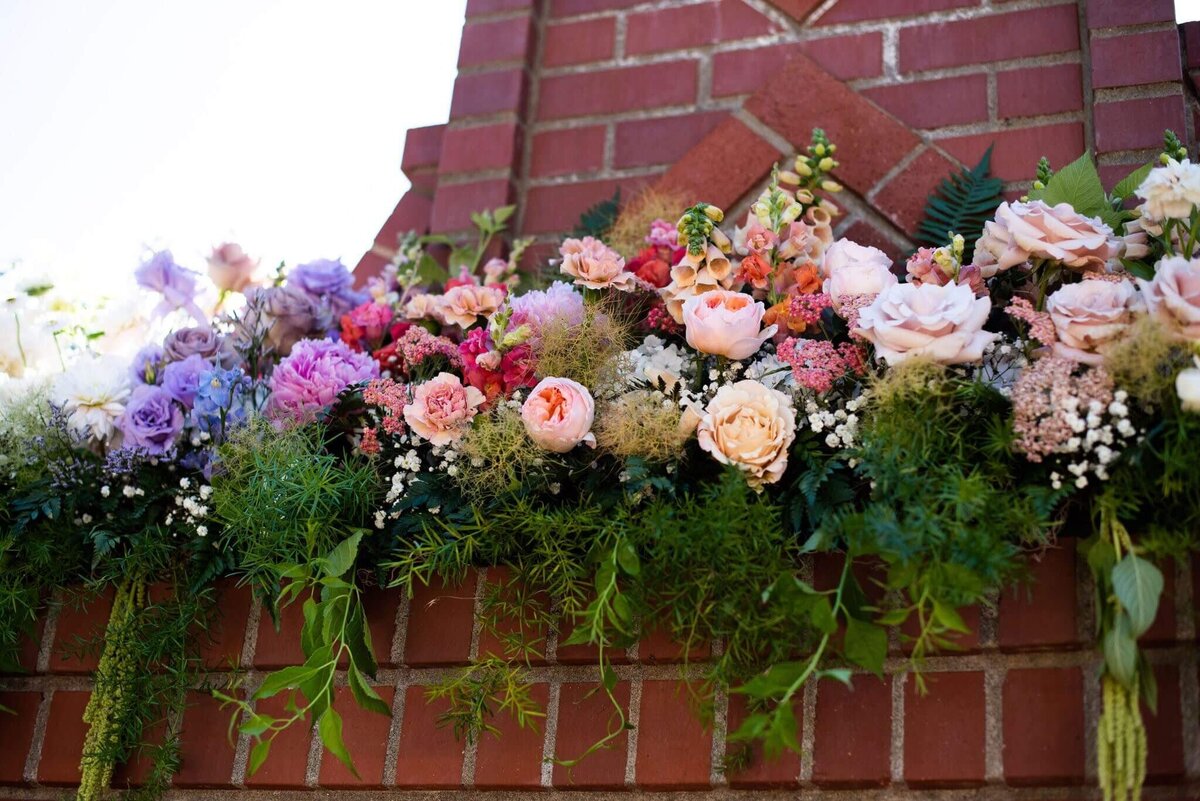 An outdoor wedding reception with a large floral installation atop a mantelpiece.