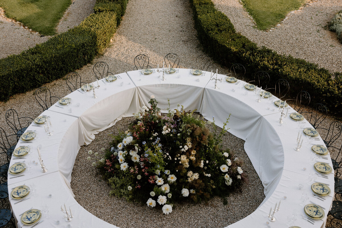 Wedding reception tables set up in a circle with a large floral arrangement in the middle 