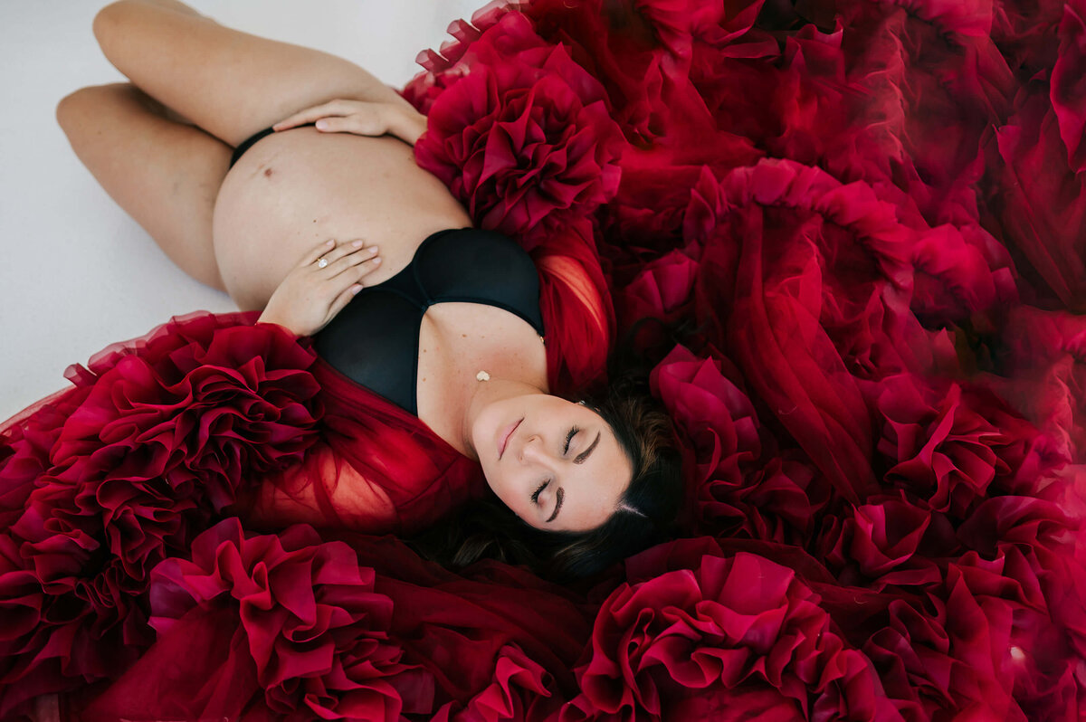 maternity photo of mom laying on floor closing eyes in maternity photography studio in Joplin MO