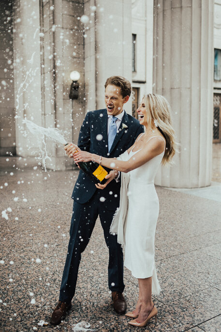 elopement couple just married celebrating popping champagne bottle