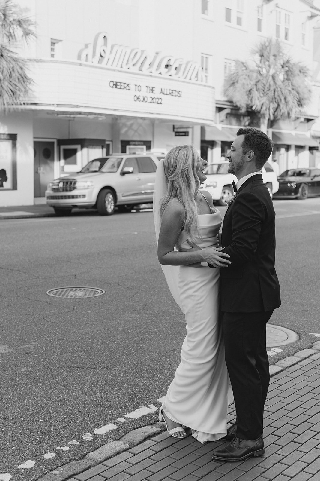 Bride and groom on King Street in downtown Charleston with custom movie marquee. Kailee DiMeglio Photography. Black and white wedding photos.