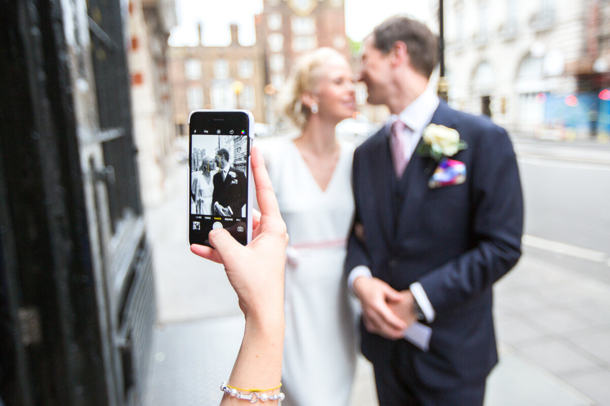 Taking a photo of bride and groom with phone