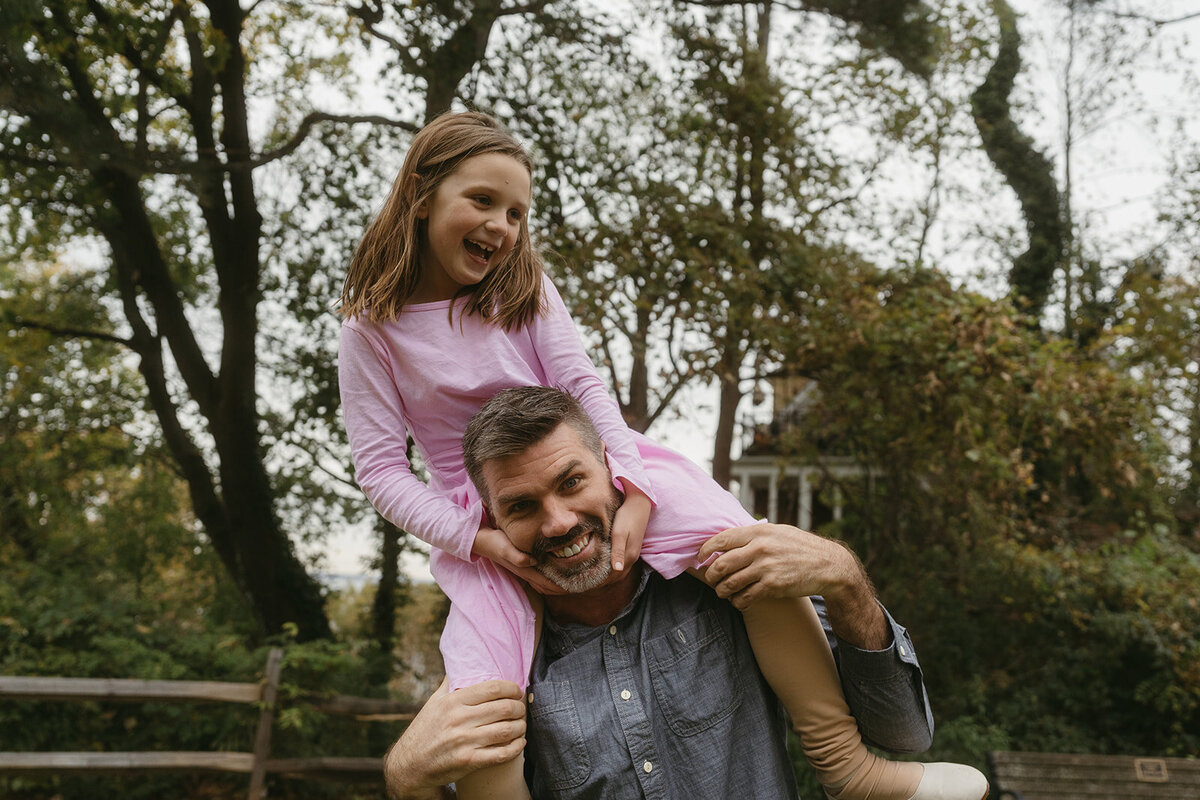 daughter sits on dad's shoulders during family photos captured by NYC family photographer Elsie Goodman 
