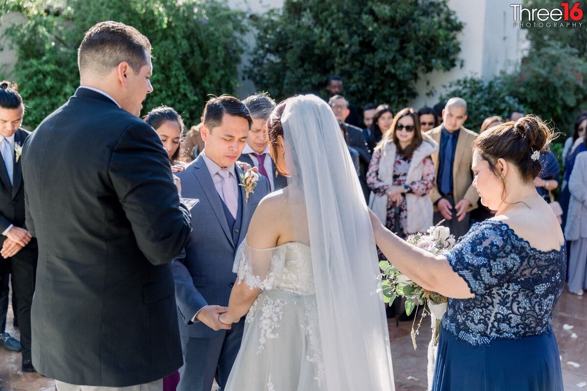 Bride and Groom bow their heads during the wedding ceremony as the officiant prays over them