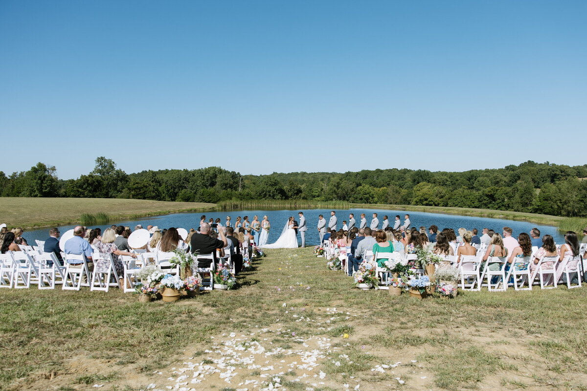 Outdoor pond ceremony with Kentucky bluegrass backdrop at Willstone Acres wedding venue