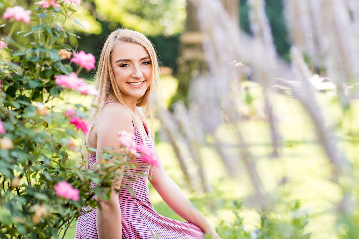 High School Senior girl poses with roses at Amber Grove venue for her senior portrait session.