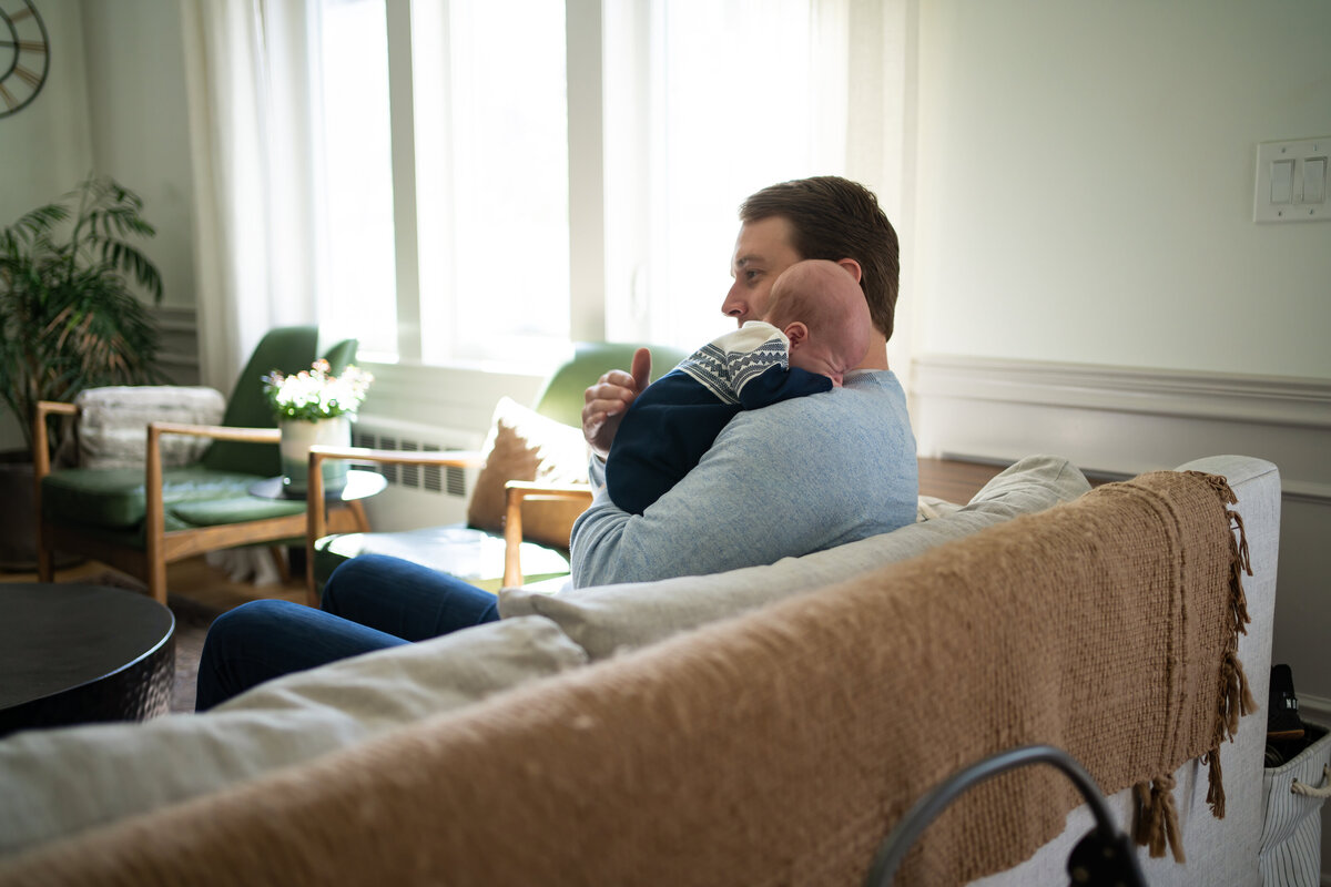 Dad sitting on couch comforting baby boy